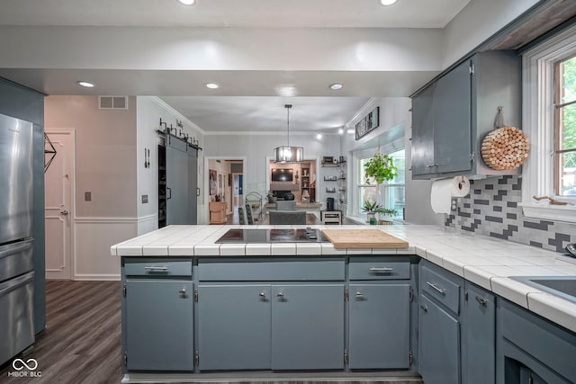 9420 N Kenwood Ave, Indianapolis, IN 46260 - kitchen with a barn door, freestanding refrigerator, a peninsula, black electric cooktop, and backsplash