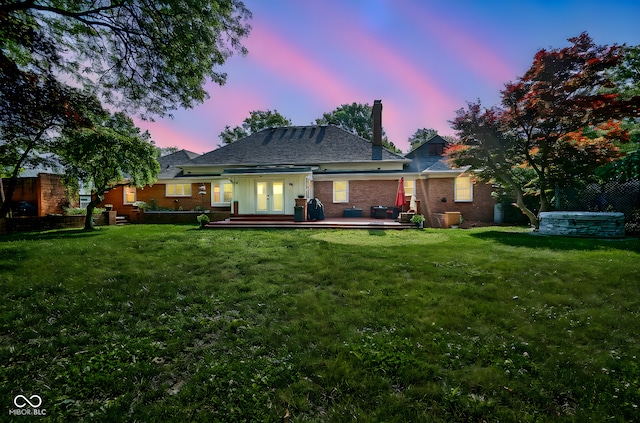 9420 N Kenwood Ave, Indianapolis, IN 46260 - back of property at dusk featuring a chimney, brick siding, and french doors