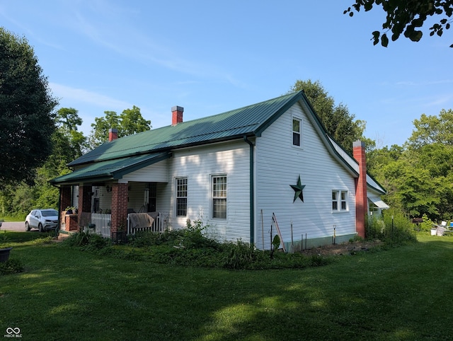180 N Pike St, Vernon, IN 47282 - view of property exterior featuring a chimney, a yard, a porch, and a metal roof