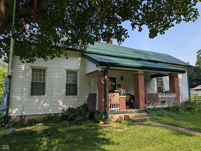 180 N Pike St, Vernon, IN 47282 - view of front of home with a porch, a chimney, a front yard, a metal roof, and brick siding