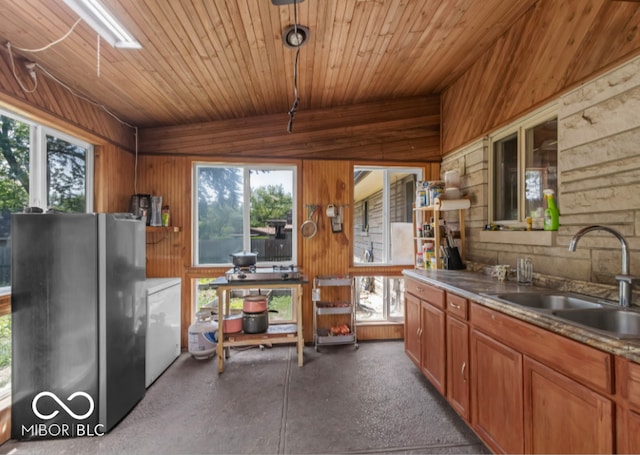 8217 S Talbott Ave, Indianapolis, IN 46227 - kitchen featuring freestanding refrigerator, wooden walls, plenty of natural light, brown cabinetry, and washer / dryer