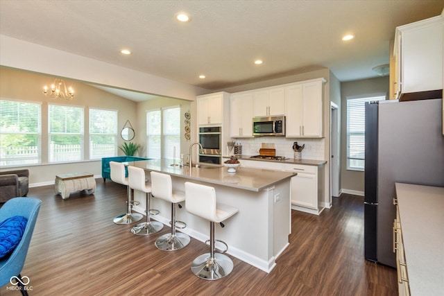 4642 Boyd Pl, Westfield, IN 46062 - kitchen with stainless steel appliances, dark wood finished floors, tasteful backsplash, a breakfast bar area, and white cabinets
