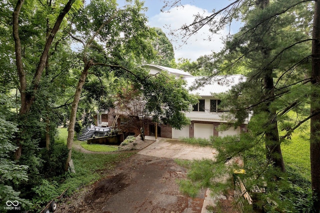 1065 E 76th St, Indianapolis, IN 46240 - view of property hidden behind natural elements with driveway, a garage, and brick siding