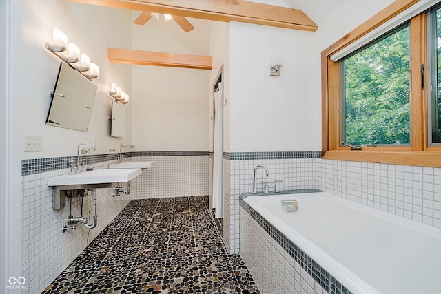 1065 E 76th St, Indianapolis, IN 46240 - full bathroom featuring a bath, tile walls, a wainscoted wall, a ceiling fan, and stone finish flooring