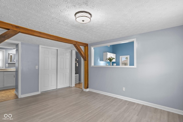 1254 Wade St, Austin, IN 47102 - unfurnished bedroom featuring wood finished floors, a closet, a textured ceiling, and connected bathroom
