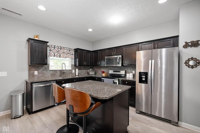 1312 Donald Pass, Greenwood, IN 46143 - kitchen with appliances with stainless steel finishes, light wood-style floors, backsplash, recessed lighting, and a textured ceiling