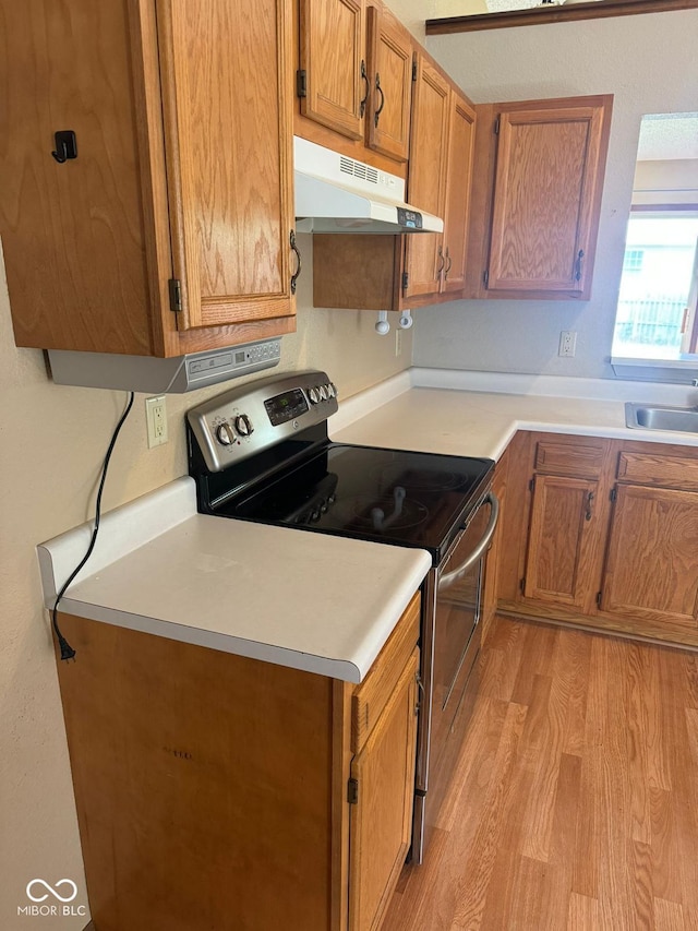 39 Meadow Creek E Boulevard, Whiteland, IN 46184 - kitchen with electric stove, under cabinet range hood, light wood-type flooring, brown cabinets, and light countertops