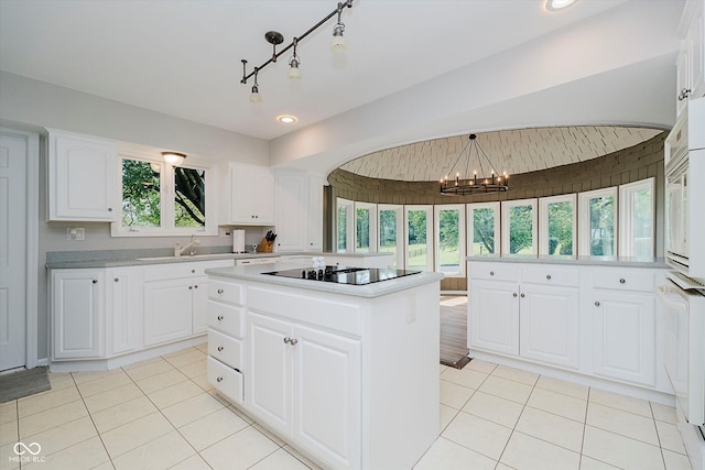 16714 Oak Rd, Westfield, IN 46074 - kitchen with black electric stovetop, a chandelier, light countertops, a kitchen island, and light tile patterned floors