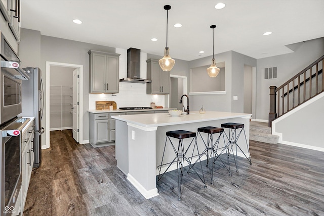 2074 Tompkins Dr, Westfield, IN 46074 - kitchen with wall chimney range hood, gray cabinetry, dark wood finished floors, a breakfast bar, and recessed lighting