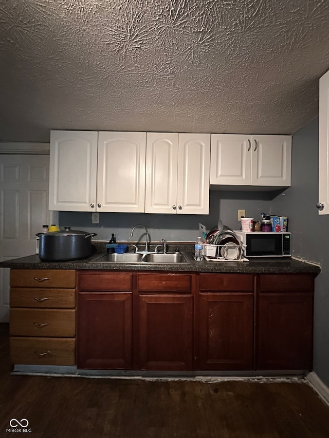 1129 N Pershing Ave, Indianapolis, IN 46222 - kitchen with black microwave, dark wood-type flooring, dark countertops, white cabinets, and a textured ceiling