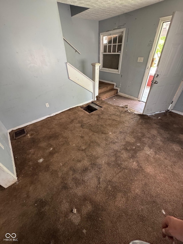 3701 E Vermont St, Indianapolis, IN 46201 - unfurnished living room with stairway, carpet flooring, and a textured ceiling