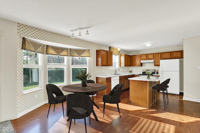 11961 Driftstone Dr, Fishers, IN 46037 - kitchen with white appliances, wallpapered walls, light countertops, a kitchen island, and brown cabinets