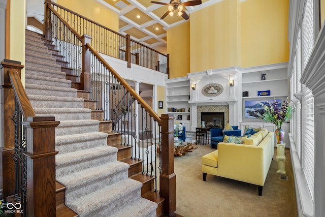 1130 Kingswood Rd S, West Lafayette, IN 47906 - carpeted living area featuring a ceiling fan, a fireplace, a towering ceiling, ornamental molding, and stairway