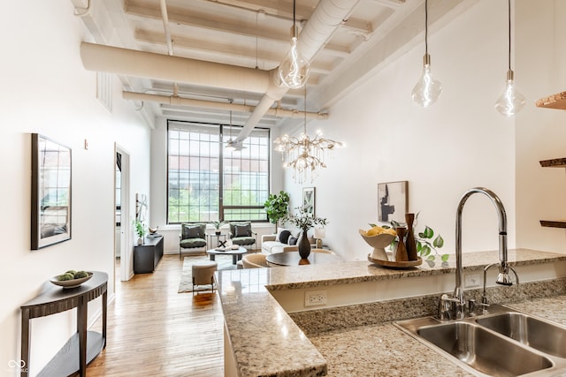 624 E Walnut St Unit 48, Indianapolis, IN 46204 - kitchen featuring light wood-type flooring, beam ceiling, a high ceiling, decorative light fixtures, and light stone countertops