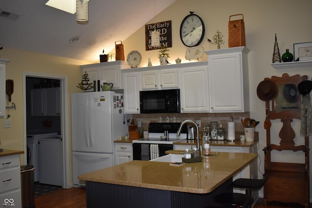 7357 Lake Lakota Dr, Indianapolis, IN 46217 - kitchen with black microwave, freestanding refrigerator, range with electric stovetop, independent washer and dryer, and vaulted ceiling