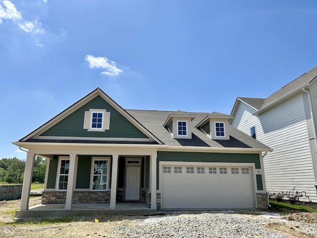 14277 Coyote Rdg, Noblesville, IN 46060 - view of front of house with stone siding, a garage, a porch, a shingled roof, and driveway