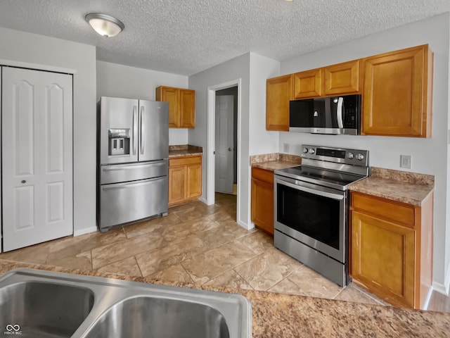 3445 Brandenburg Blvd, Indianapolis, IN 46239 - kitchen with appliances with stainless steel finishes, a textured ceiling, and brown cabinets