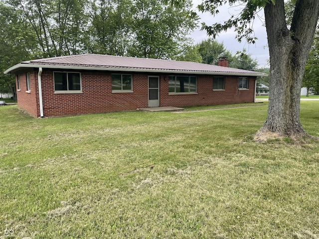 406 N Main St, Cloverdale, IN 46120 - view of front of home featuring a front yard, brick siding, a chimney, and a metal roof