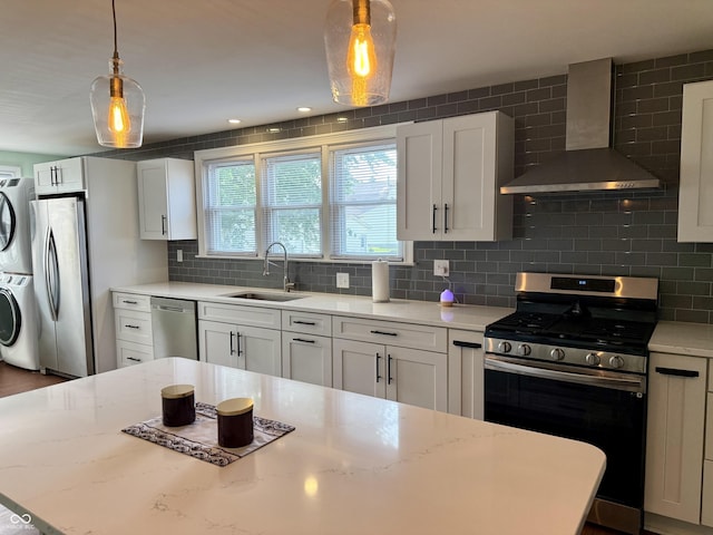 820 N Broadway St, Greensburg, IN 47240 - kitchen featuring wall chimney range hood, appliances with stainless steel finishes, estacked washer and dryer, tasteful backsplash, and white cabinetry