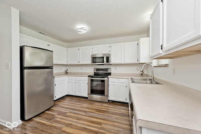 11320 Lynchburg Way, Indianapolis, IN 46229 - kitchen with stainless steel appliances, light countertops, white cabinets, and wood finished floors