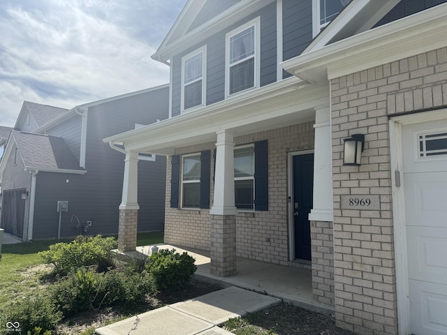 8969 Faulkner Dr, Indianapolis, IN 46239 - doorway to property featuring a porch, a garage, and brick siding