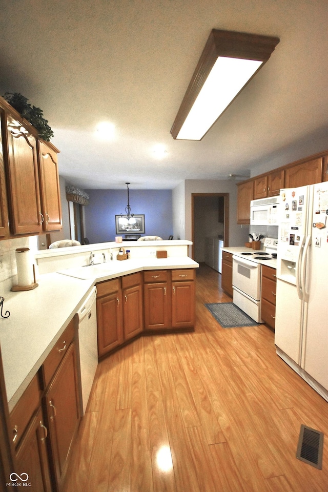 5943 Red Maple Dr, Indianapolis, IN 46237 - kitchen featuring white appliances, a peninsula, light countertops, brown cabinets, and light wood finished floors