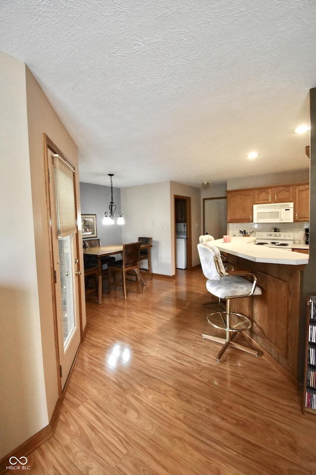 5943 Red Maple Dr, Indianapolis, IN 46237 - kitchen featuring white appliances, light wood-style floors, brown cabinetry, light countertops, and a kitchen breakfast bar