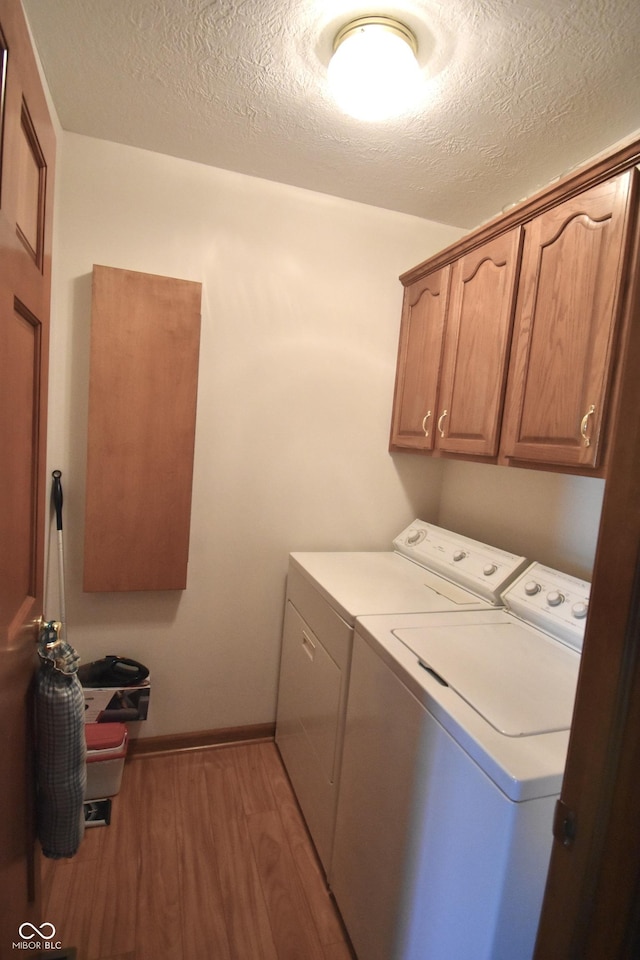 5943 Red Maple Dr, Indianapolis, IN 46237 - laundry area featuring separate washer and dryer, cabinet space, light wood-style floors, and a textured ceiling