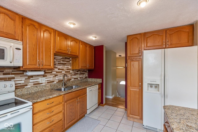 5802 Rymark Ct, Indianapolis, IN 46250 - kitchen featuring white appliances, backsplash, light tile patterned floors, light stone countertops, and brown cabinets