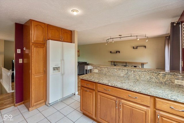 5802 Rymark Ct, Indianapolis, IN 46250 - kitchen featuring white refrigerator with ice dispenser, light tile patterned floors, brown cabinetry, and light stone counters