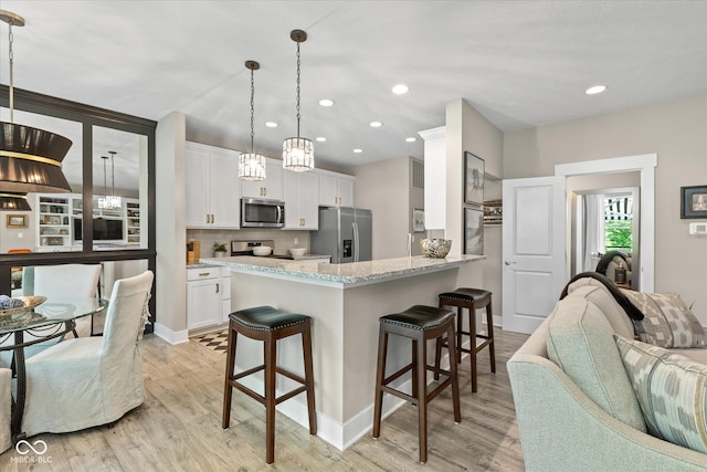 14442 Treasure Creek Ln, Fishers, IN 46038 - kitchen featuring appliances with stainless steel finishes, open floor plan, a kitchen bar, light wood-style floors, and recessed lighting