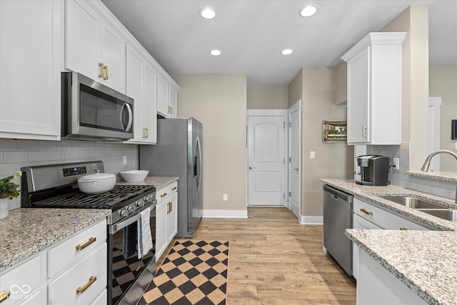 14442 Treasure Creek Ln, Fishers, IN 46038 - kitchen featuring appliances with stainless steel finishes, white cabinetry, light wood-style flooring, recessed lighting, and light stone counters