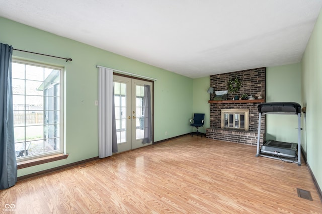 8306 Corkwood Dr, Indianapolis, IN 46227 - unfurnished living room with french doors, light wood-style floors, plenty of natural light, and a brick fireplace