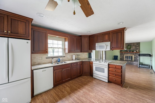 8306 Corkwood Dr, Indianapolis, IN 46227 - kitchen featuring white appliances, light wood-style flooring, backsplash, a ceiling fan, and a brick fireplace