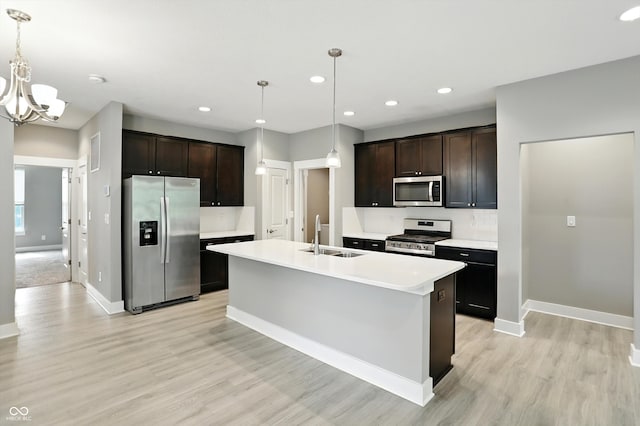 14474 Treasure Creek Ln, Fishers, IN 46038 - kitchen with appliances with stainless steel finishes, a chandelier, recessed lighting, dark brown cabinetry, and light wood-style flooring