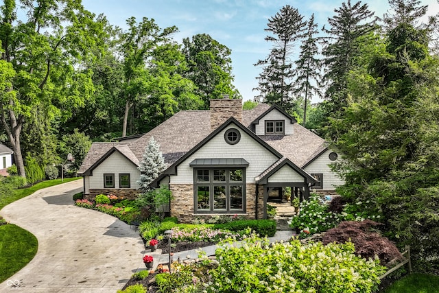 8651 Emerald Ln, Indianapolis, IN 46260 - view of front of property featuring stone siding, a chimney, a shingled roof, and driveway