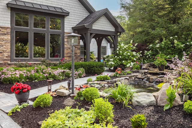 8651 Emerald Ln, Indianapolis, IN 46260 - entrance to property with a small pond, stone siding, and a standing seam roof