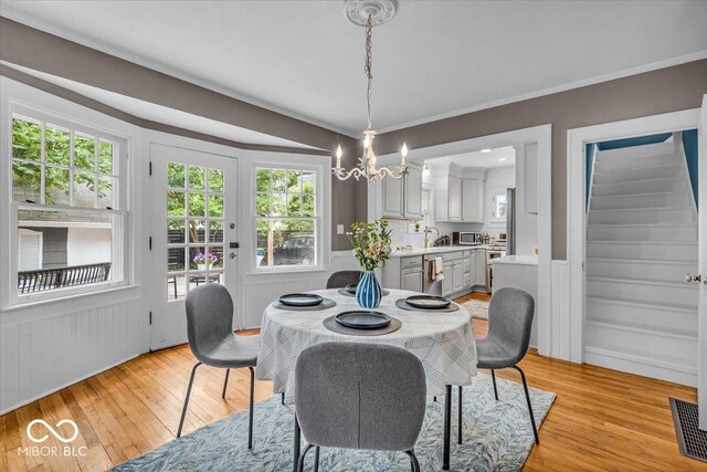 4732 N Kenwood Ave, Indianapolis, IN 46208 - dining space featuring light wood-type flooring, a chandelier, stairs, and crown molding