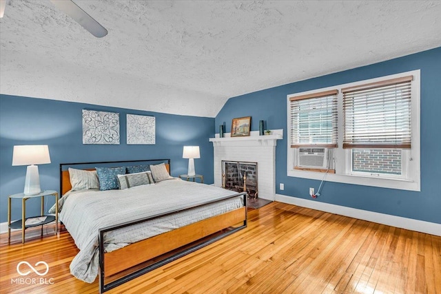 4732 N Kenwood Ave, Indianapolis, IN 46208 - bedroom featuring a textured ceiling, vaulted ceiling, wood-type flooring, a fireplace, and cooling unit