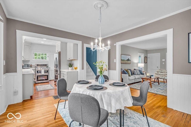 4732 N Kenwood Ave, Indianapolis, IN 46208 - dining room featuring light wood-style flooring, a wainscoted wall, a chandelier, and crown molding