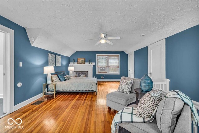 4732 N Kenwood Ave, Indianapolis, IN 46208 - bedroom with wood-type flooring, a textured ceiling, vaulted ceiling, ceiling fan, and a brick fireplace