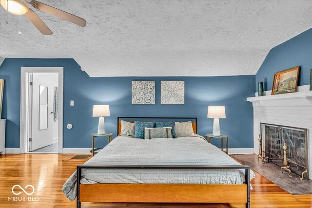 4732 N Kenwood Ave, Indianapolis, IN 46208 - bedroom with vaulted ceiling, wood finished floors, ceiling fan, a textured ceiling, and a brick fireplace