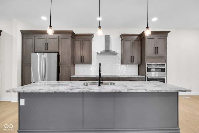 2031 Central Ave, Indianapolis, IN 46202 - kitchen with wall chimney range hood, appliances with stainless steel finishes, a center island with sink, dark brown cabinets, and recessed lighting