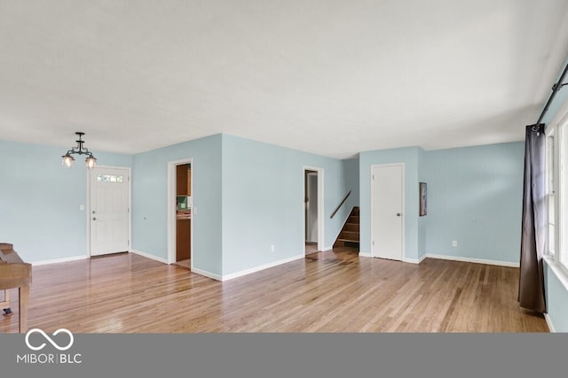 3630 E Morningside Dr, Bloomington, IN 47408 - unfurnished living room with a chandelier, light wood-style floors, and stairs