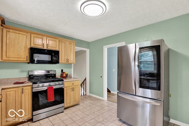 3630 E Morningside Dr, Bloomington, IN 47408 - kitchen with stainless steel appliances, light countertops, light brown cabinets, a textured ceiling, and light tile patterned flooring