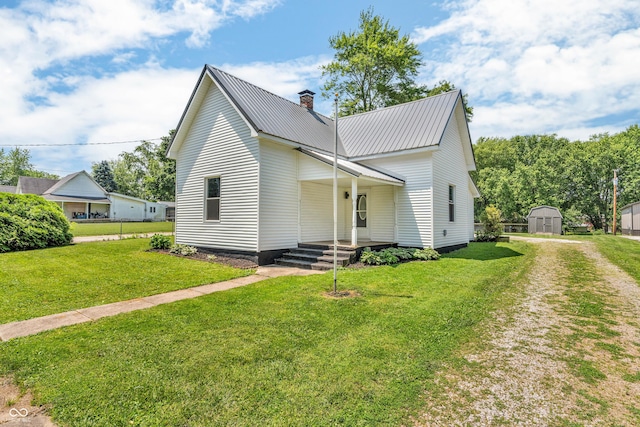 404 W St, Darlington, IN 47940 - view of front facade featuring a chimney, a porch, a metal roof, a storage unit, and a front lawn