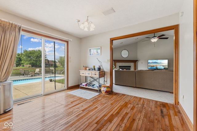 6629 Woodcrest Dr, Avon, IN 46123 - unfurnished living room featuring hardwood / wood-style flooring, a chandelier, a lit fireplace, a ceiling fan, and vaulted ceiling