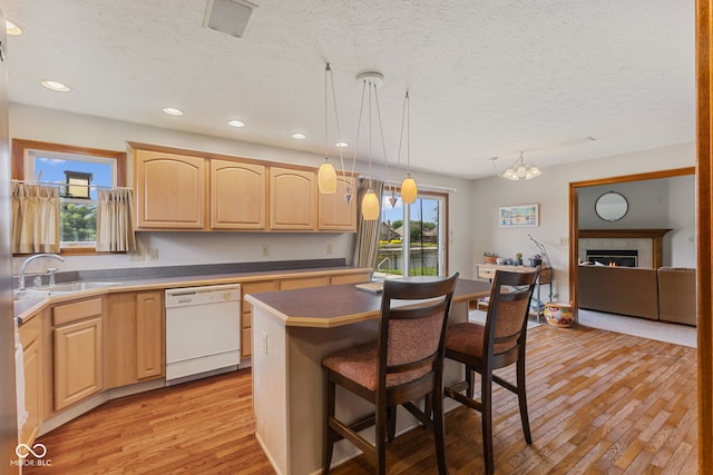 6629 Woodcrest Dr, Avon, IN 46123 - kitchen with dishwasher, light brown cabinetry, a breakfast bar, a textured ceiling, and light wood-type flooring
