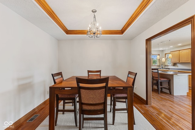 6629 Woodcrest Dr, Avon, IN 46123 - dining room featuring a chandelier, light wood-style flooring, a tray ceiling, and ornamental molding