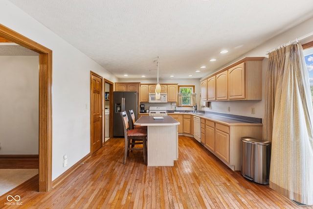 6629 Woodcrest Dr, Avon, IN 46123 - kitchen featuring white appliances, light brown cabinets, light wood-type flooring, a kitchen island, and a kitchen breakfast bar